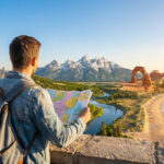 Un homme avec une carte et un sac à dos contemple un panorama composite des États-Unis: ville, montagnes, désert, plage.