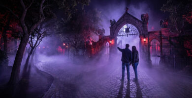 Un couple contemple un portail gothique brumeux lors d'une soirée Halloween Horror Nights.