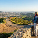 Un couple de randonneurs regarde le panorama urbain de Los Angeles depuis une colline surplombant la ville.