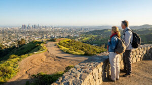 Un couple de randonneurs regarde le panorama urbain de Los Angeles depuis une colline surplombant la ville.