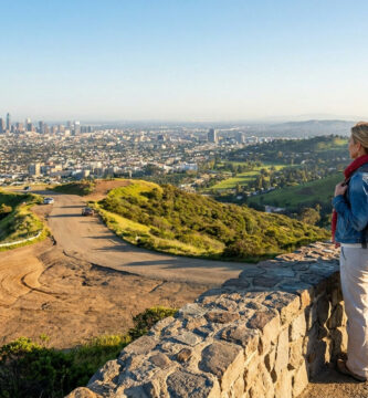 Un couple de randonneurs regarde le panorama urbain de Los Angeles depuis une colline surplombant la ville.