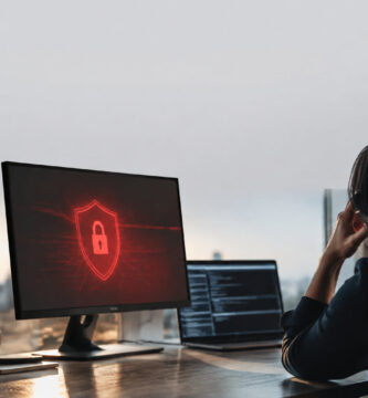 Une personne travaillant sur ordinateur face à une alerte de cybersécurité affichant un bouclier rouge avec un cadenas.